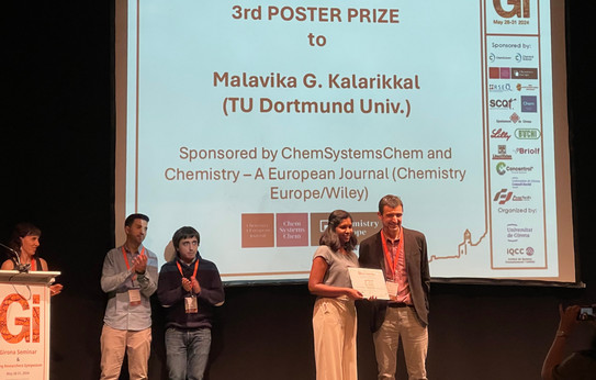 Malavika receiving her poster award on the stage of the Girona Seminar.